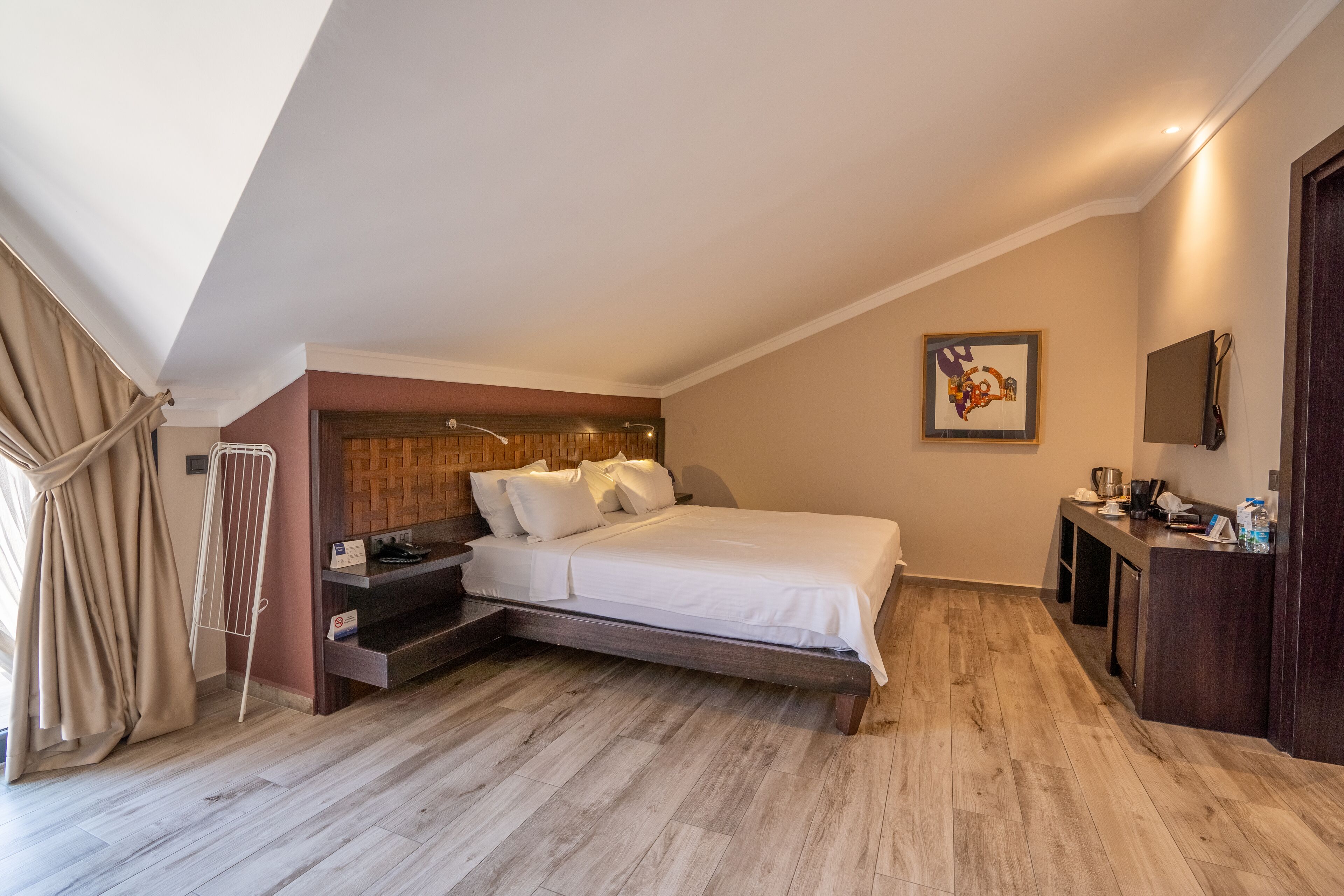 Un dormitorio con cama, escritorio, silla, radiador y un cuadro en la pared.