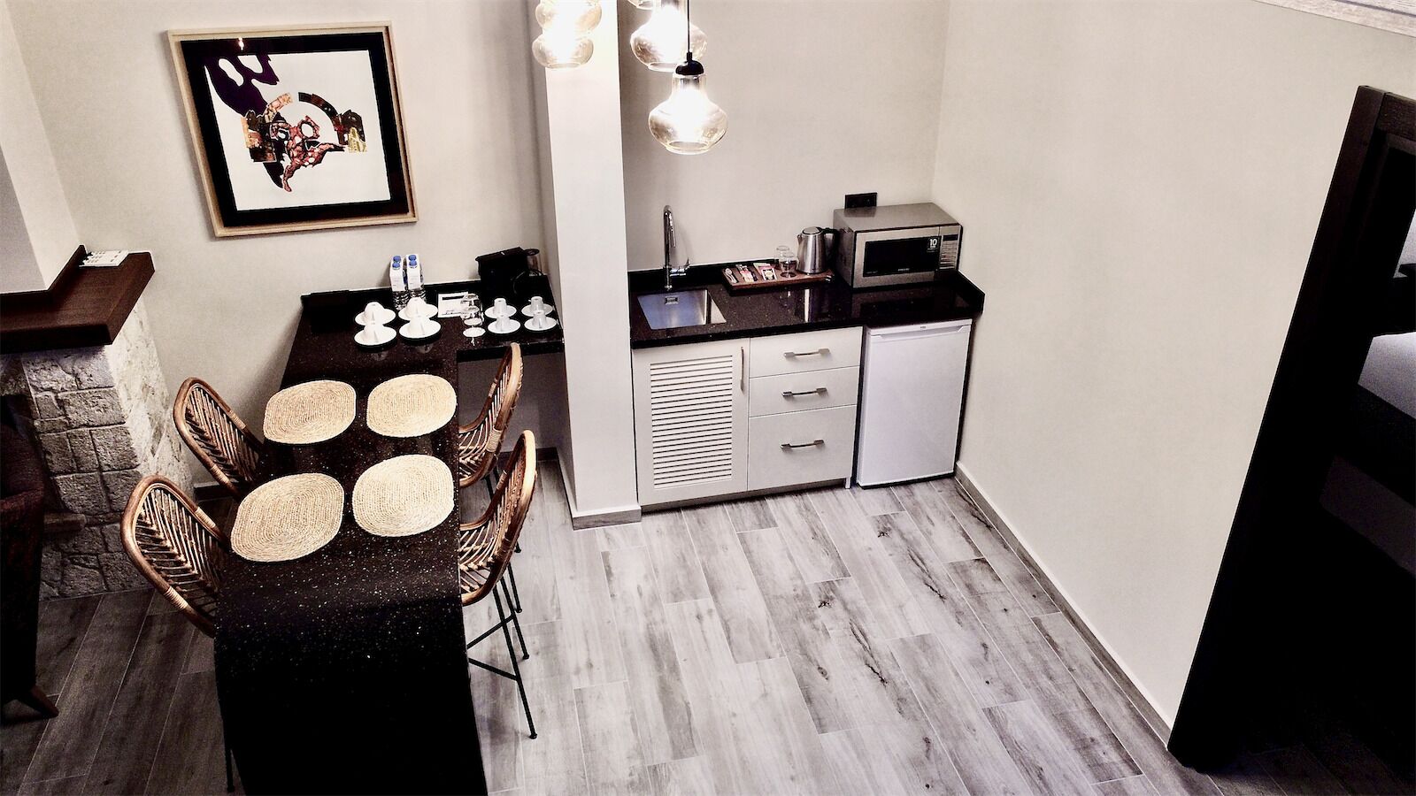A compact kitchen with a dining area, featuring a microwave, sink, and a small refrigerator.