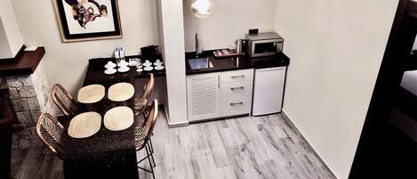 A compact kitchen with a dining area, featuring a microwave, sink, and a small refrigerator.