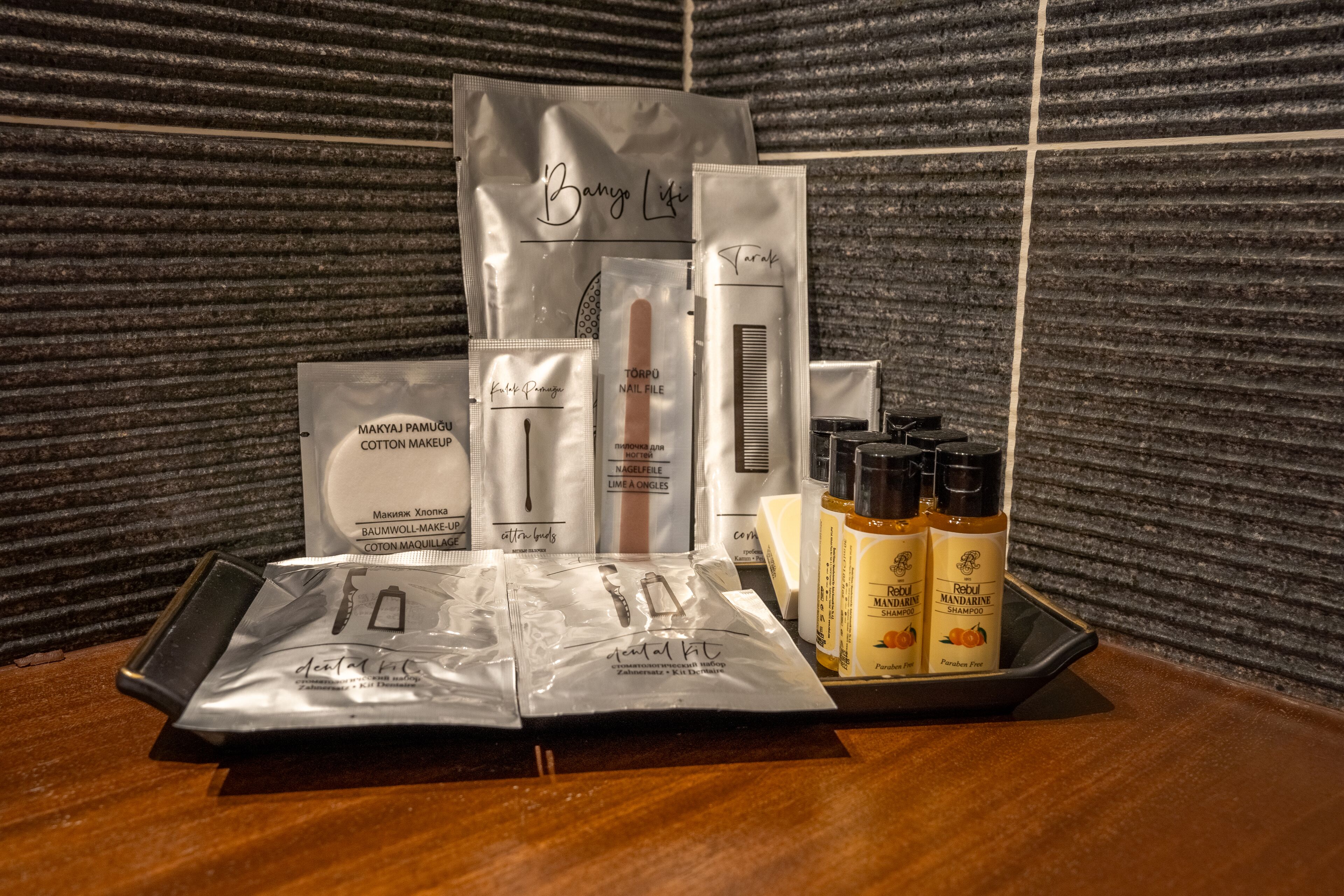 A tray with various personal care items including cotton makeup, nail file, and shampoo.