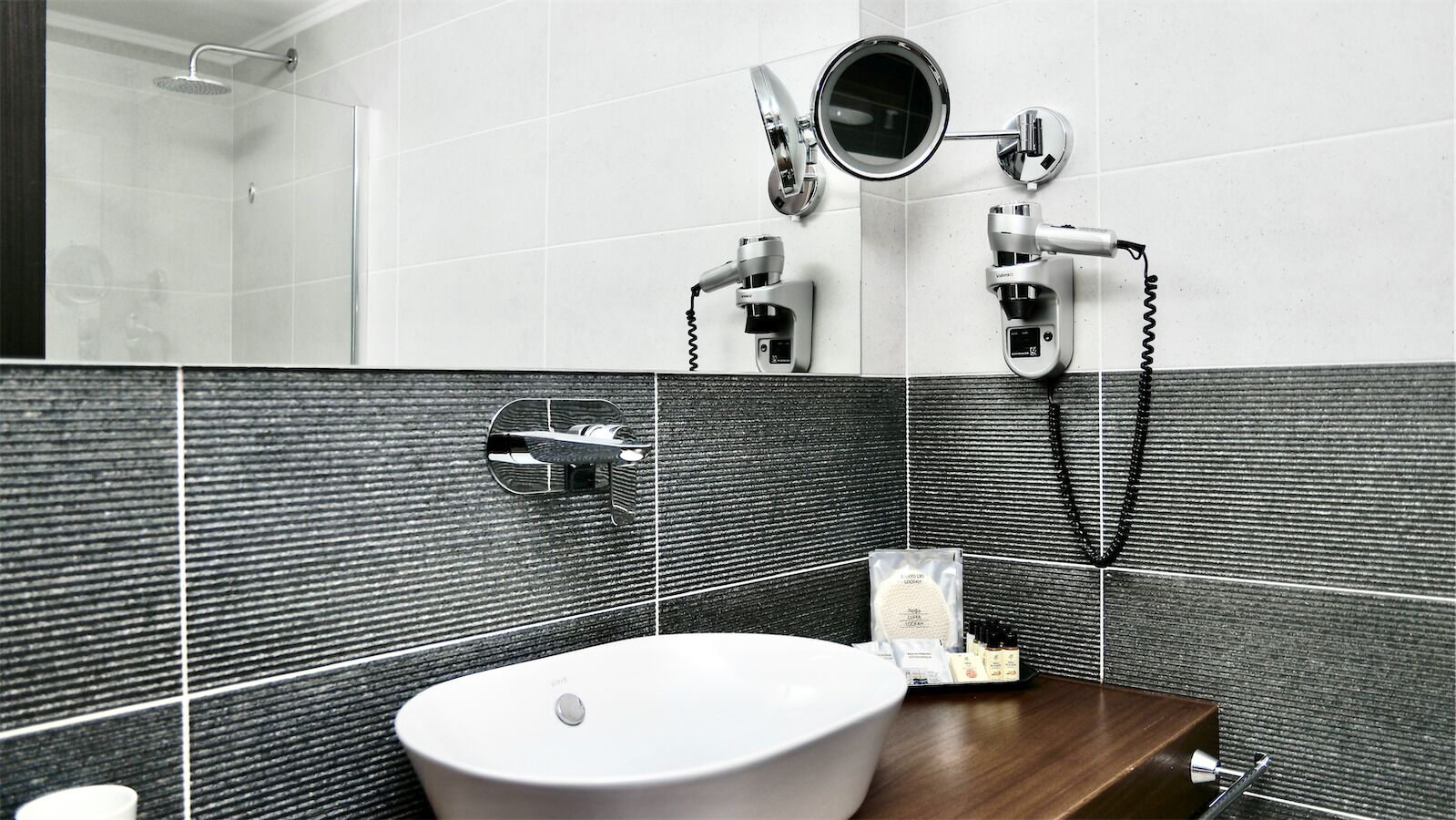 A bathroom with a white sink, a mirror, and a handheld showerhead.