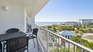 A balcony with a view of the beach, a table, and chairs. - Seacrest 504 is a Gulf Front 2 BR on Okaloosa Island by RedAwning (Fort Walton Beach)