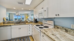 A modern kitchen with white cabinets, a granite countertop, a built-in microwave, and a stove.