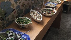 Pöytä, jossa on erilaisia ruokia, maljakko kukkineen ja ikkuna, josta on näkymä.
