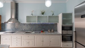 A modern kitchen with a stainless steel range hood, a double sink, and a built-in oven. There are three potted plants on the countertop and a white cabinet with drawers below. - HomeForGuest NEW Duplex with Rooftop next to Arucas Cathedral (Arucas)