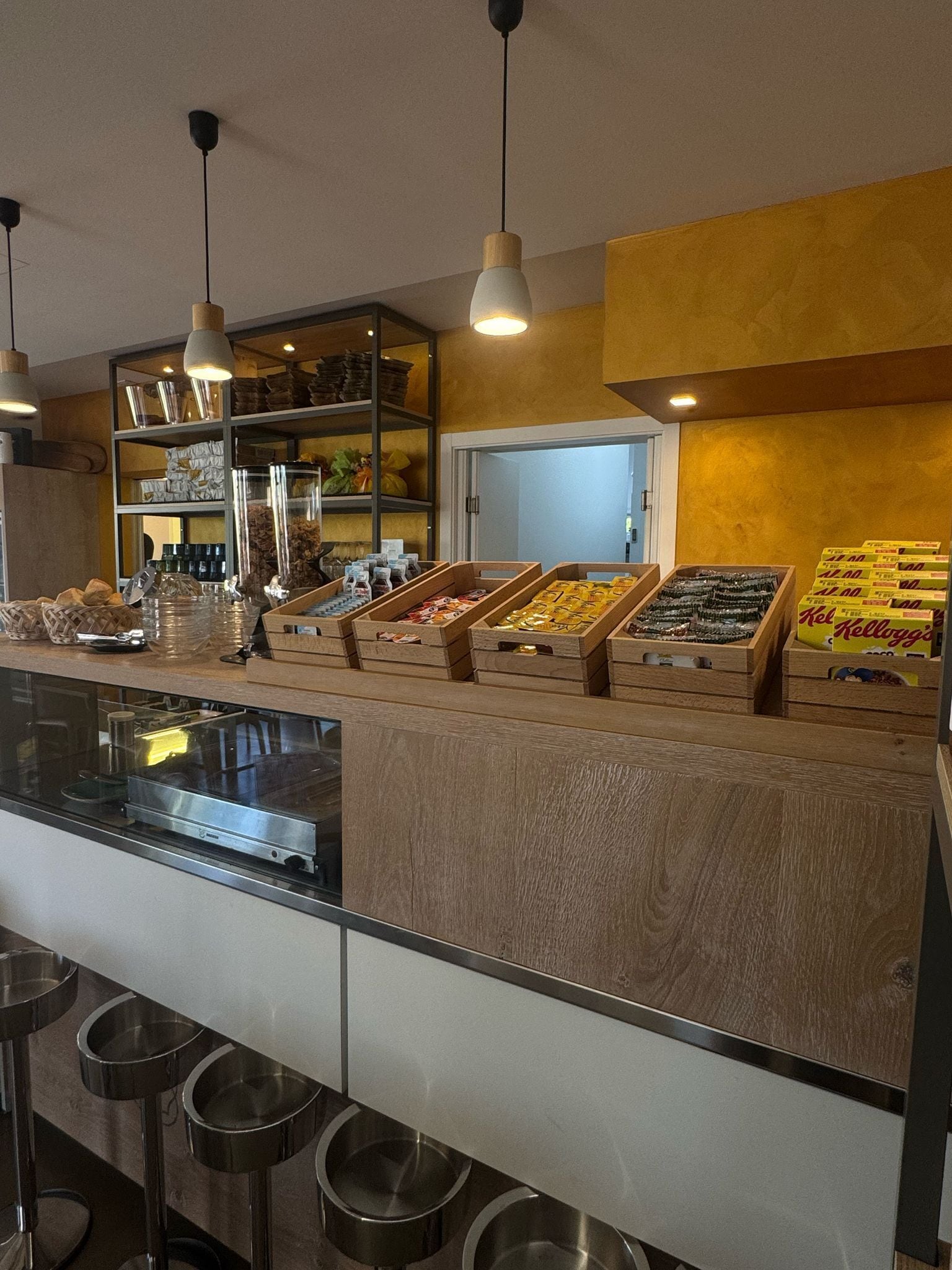 Un bar proposant une variété de plats, présentés dans des caisses en bois, une vitrine réfrigérée et un comptoir avec des tabourets.