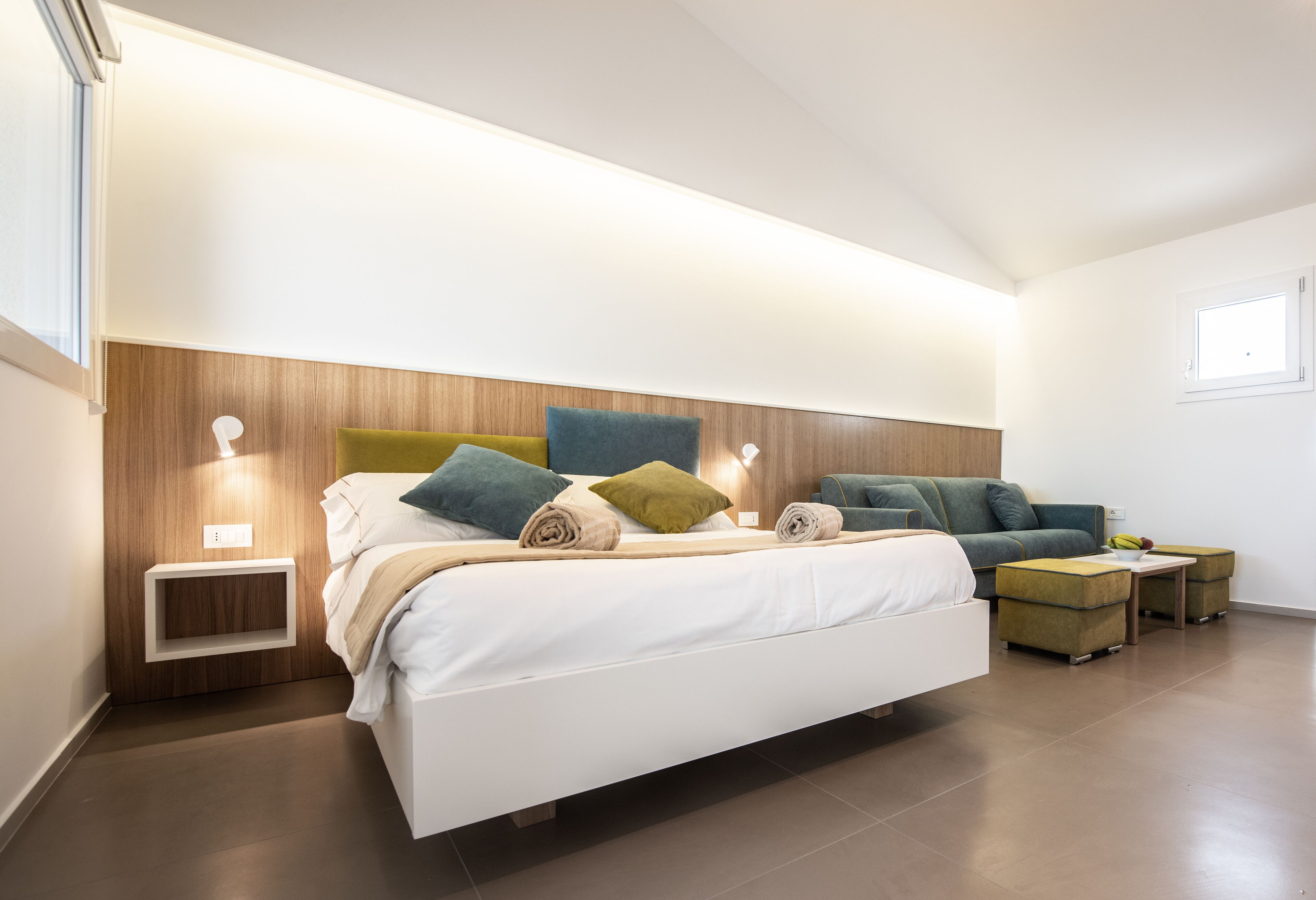 Une chambre à coucher moderne avec un lit, des tables de chevet et un canapé.