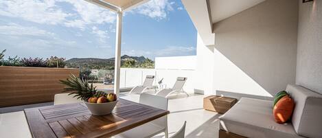 A modern outdoor seating area with a table, chairs, and a sofa.