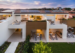 A modern multi-story house with a rooftop garden, outdoor seating area, and a visible kitchen. - Montepetrosu Charming House (San Teodoro)