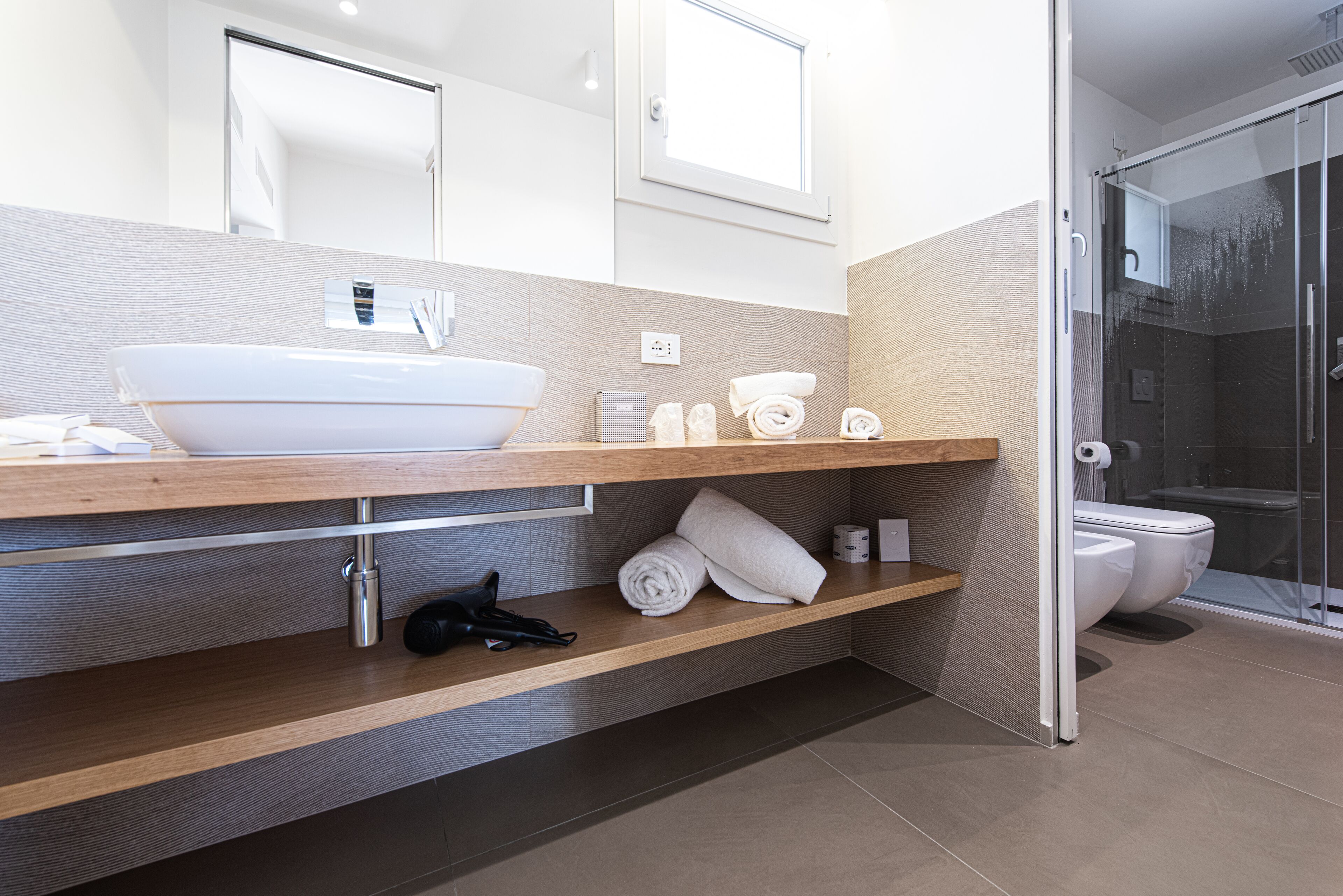 Une salle de bain moderne avec un grand lavabo blanc, un miroir et un espace douche.
