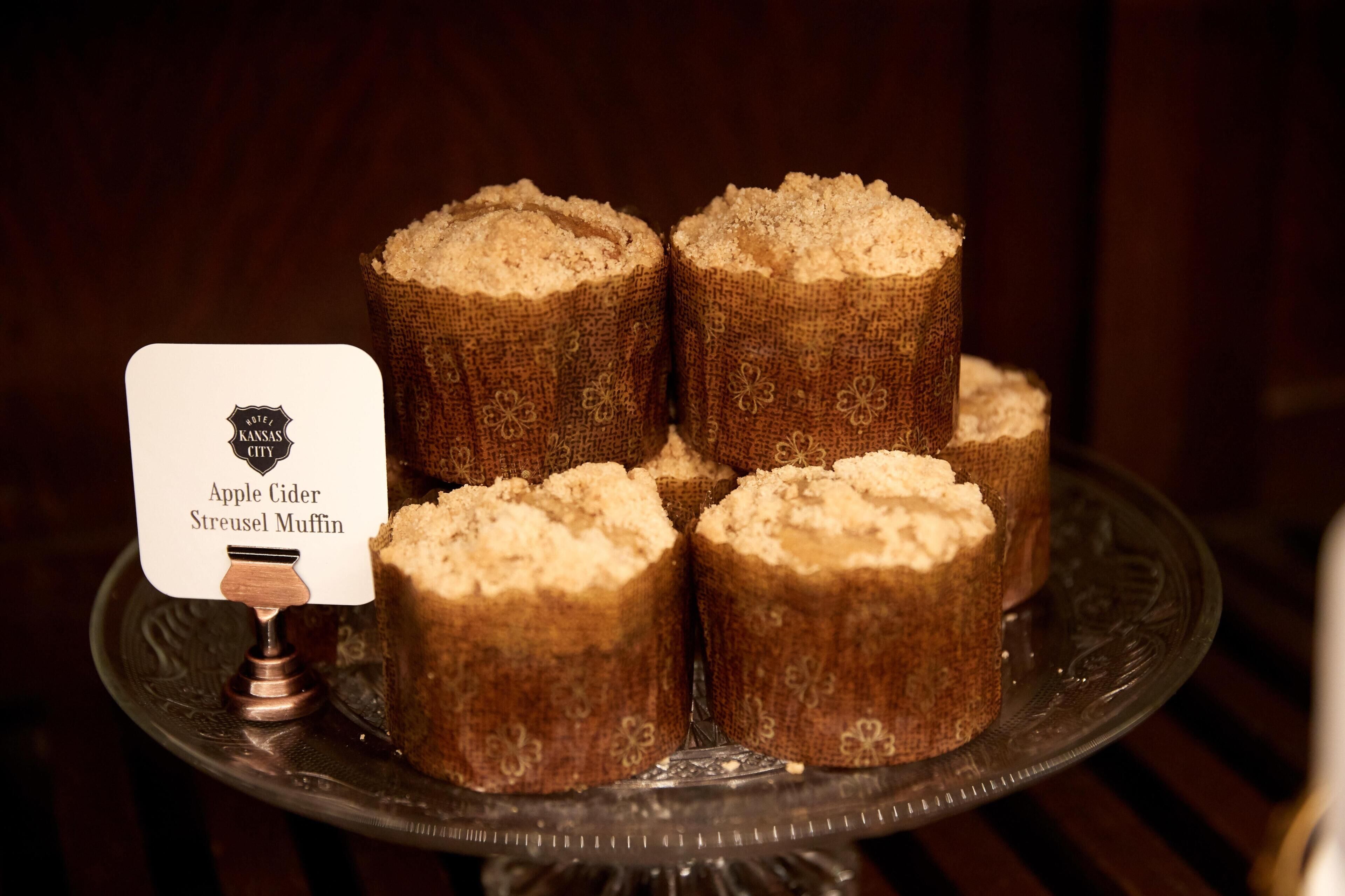 A tray with four apple cider streusel muffins on a decorative plate.