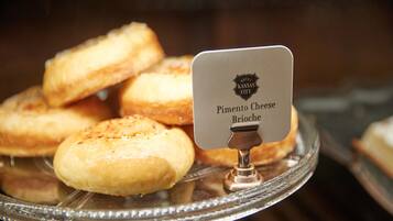 Eine Auswahl an Pimento Cheese Brioche Gebäcken auf einer Glasplatte, mit einem Schild, das den Hotelnamen angibt.