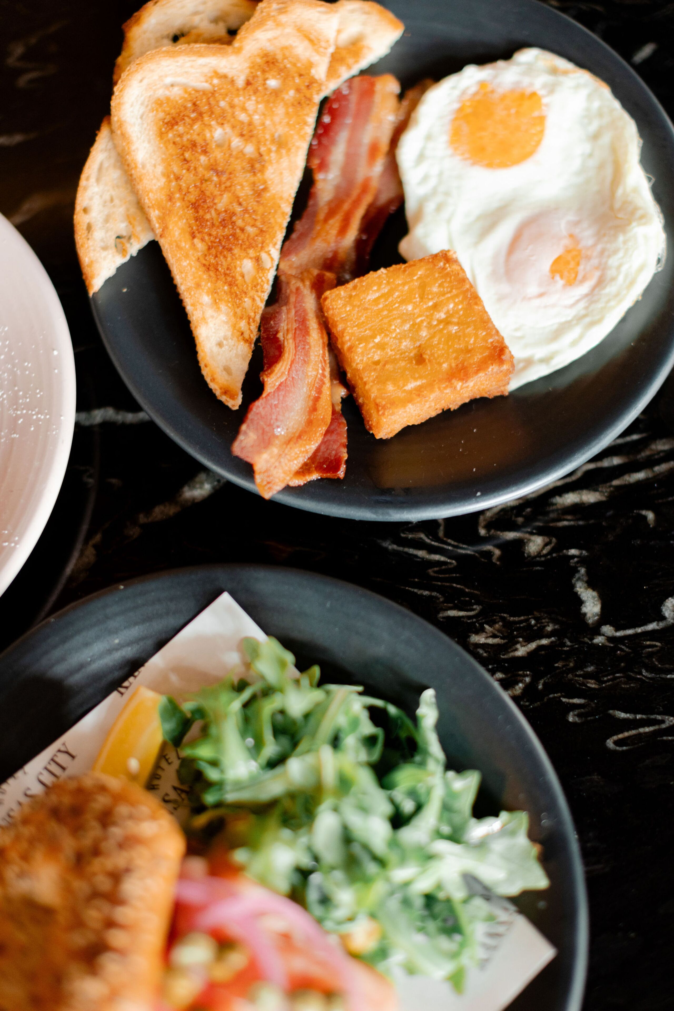 A breakfast plate with toast, bacon, and a fried egg.