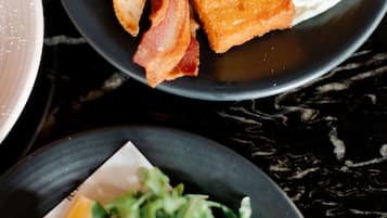 A breakfast plate with toast, bacon, and a fried egg.