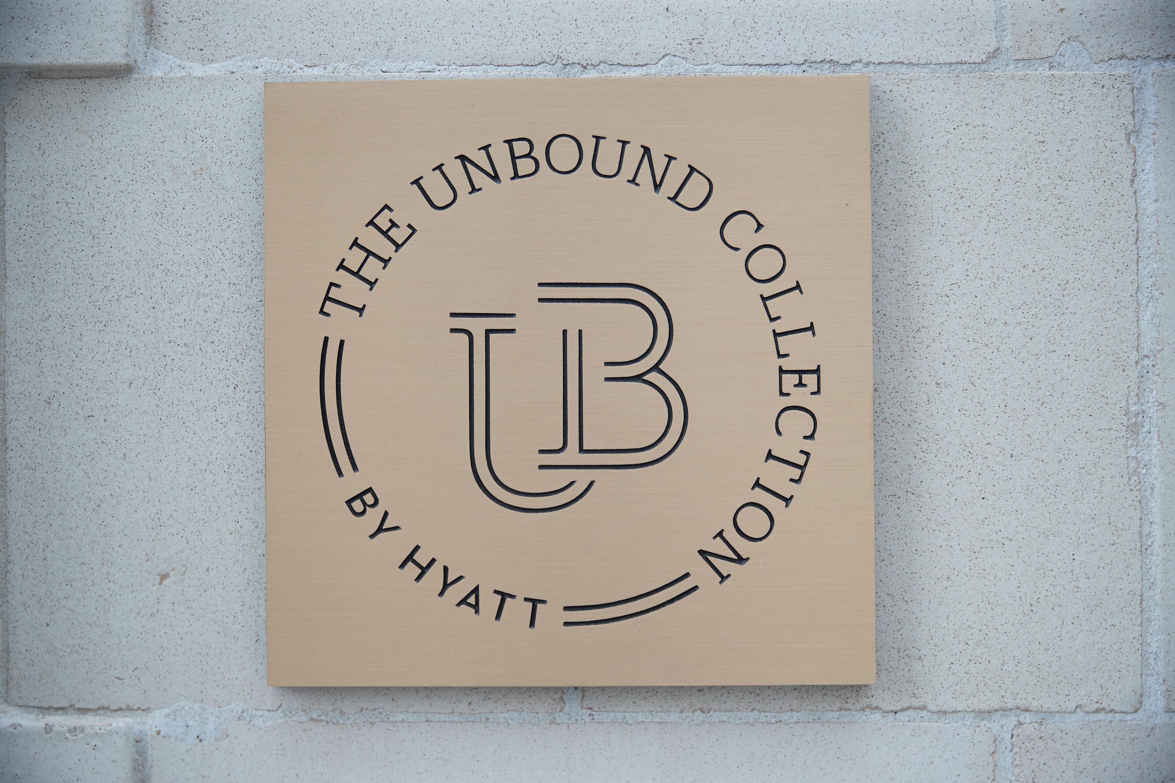 Un letrero con el texto 'THE UNBOUND COLLECTION BY HYATT' sobre un fondo color beige.