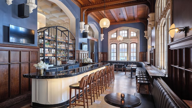 A bar area with a long counter, multiple bar stools, and a seating area with tables and benches.