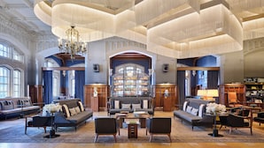 A spacious lobby with a grand chandelier, seating areas, and a bar.
