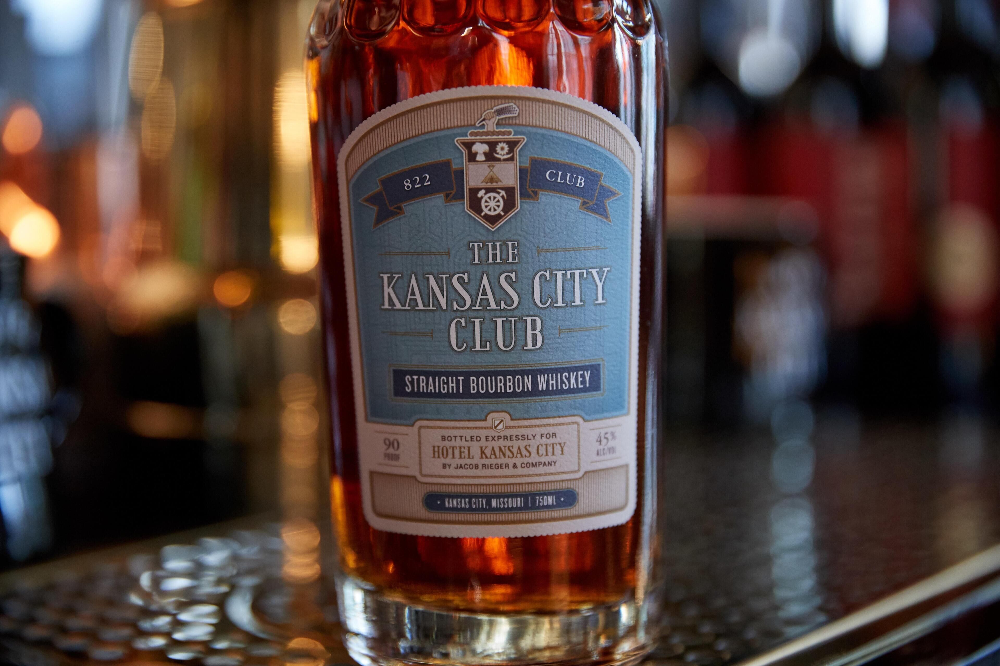 A bottle of The Kansas City Club Straight Bourbon Whiskey with a label indicating it is bottled for Hotel Kansas City.