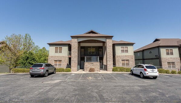 A two-story building with a central entrance, parking lot, and two cars parked in front.