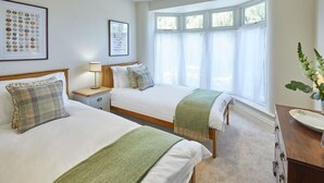 A bedroom with two beds, a bedside table with a lamp, a window with curtains, and a framed picture on the wall. - Host & Stay | Princes Road (Saltburn-by-the-Sea)