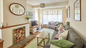 A living room with a fireplace, a sofa set, a television, and framed pictures on the walls. - Host & Stay | Princes Road (Saltburn-by-the-Sea)