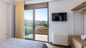Ein Schlafzimmer mit einem Bett, einem Fernseher, einer Schiebetür zu einem Balkon und einem weißen Heizkörper.