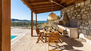 Eine Terrassengruppe im Freien mit einer Steinwand, einer Holzbeschichtung und einem Esstisch für sechs Personen.