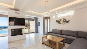 Ein modernes Wohnzimmer mit einem großen Flachbildfernseher, einem grauen Sofa, einem Holztisch und einem dekorativen Wandbild.