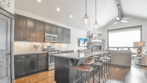 Una cocina moderna con armarios oscuros, una isla central con taburetes y un amplio ventanal que proporciona luz natural.
