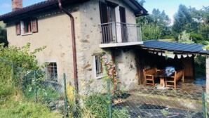 Une maison de campagne en pierre, dotée d’un balcon, d’une véranda et d’un jardin clos.