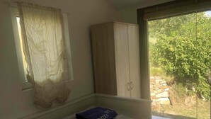 Une chambre avec un lit, une armoire et une fenêtre donnant sur un paysage verdoyant.