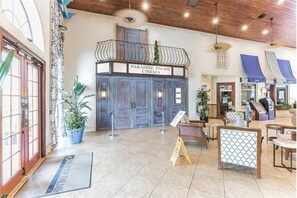 A cinema with a balcony, potted plants, and a reception area with a sign.