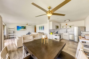 A modern kitchen with a central island, white cabinetry, stainless steel appliances, and a ceiling fan.