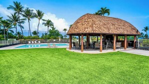 A gazebo with a tiled roof, a swimming pool, and a well-maintained lawn. - Newly Renovated Condo with SUP Paddle Boards and Golf Clubs Included (Kailua-Kona)