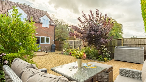 Un patio con mobiliario de mimbre, una mesa y una parrilla.
