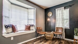 A room with a large window, two chairs, a small table, and a potted plant. - The Blue Cactus in Downtown McKinney (Mckinney)