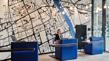 A modern reception area with a large black and white map mural, blue seating, and hanging light fixtures.