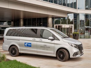 A silver van with "Holiday Inn Express" branding parked in front of a hotel entrance. - Holiday Inn Express Warsaw - The HUB by IHG (Warsaw)