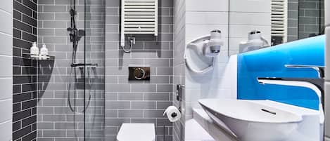Un baño moderno con ducha de vidrio, inodoro blanco y lavamanos con detalles en una pared azul.