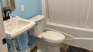 Een badkamer met een wastafel, toilet en bad.