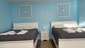 Een slaapkamer met twee bedden, een nachtkastje en decoratieve wandkunst.