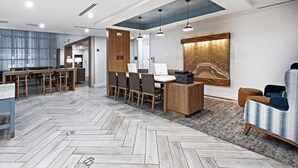 A modern hotel lobby with a herringbone floor, a reception desk, a seating area, and a large abstract wall art piece. - Staybridge Suites Waco South - Woodway by IHG (Waco)