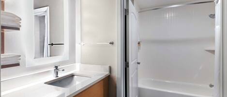 A modern bathroom with a white sink, mirror, and bathtub.