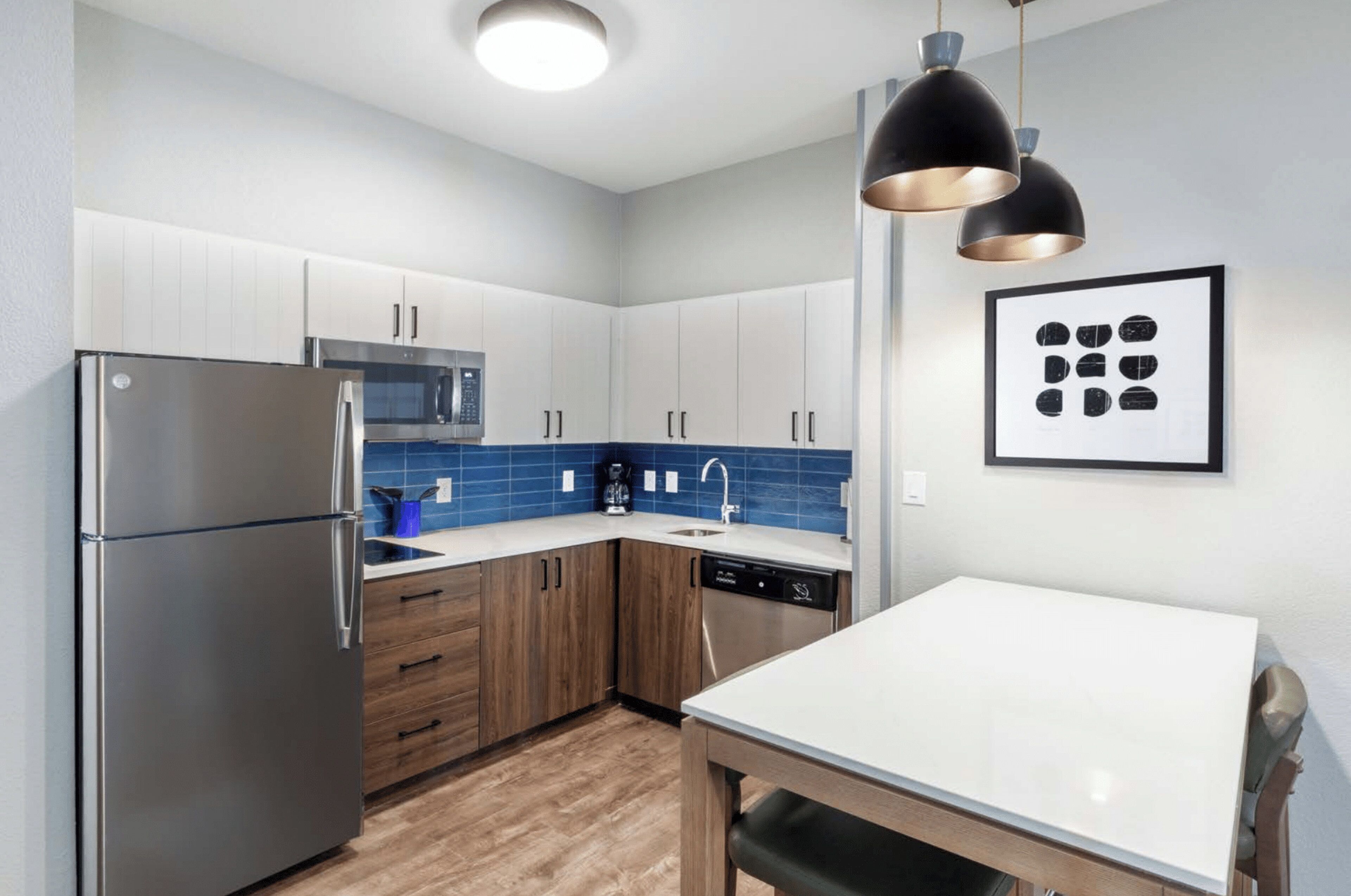 A modern kitchen with stainless steel appliances, wooden cabinets, and a blue tiled backsplash.