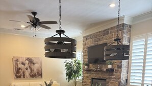 Una cocina moderna con una isla grande, hornos integrados y una pared decorativa de piedra.