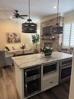 A modern kitchen with a large island, built-in ovens, and a stone accent wall.