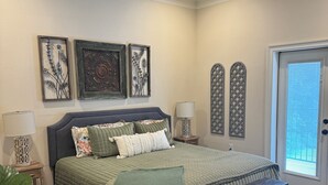 Un dormitorio con cama, ventilador de techo, un banco y detalles decorativos en la pared.