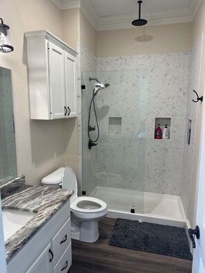 Een badkamer met douche, toilet en wastafel.
