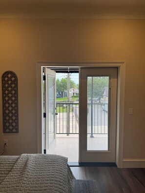 A room with a bed, a door leading to a balcony, and a decorative wall piece.