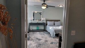 A bedroom with a bed, a dresser, a mirror, a ceiling fan, and a light fixture. - Lou's Place @ COLE'S LODGE (Carrabelle)